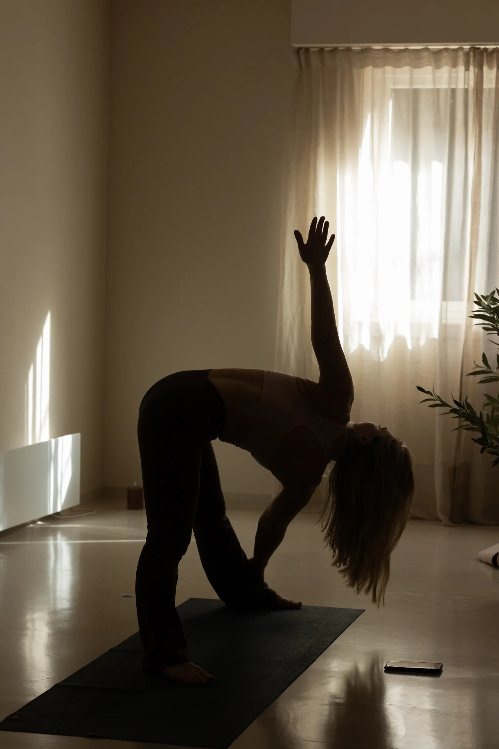 Rolig yogaposisjon i mykt motlys fra vinduet
