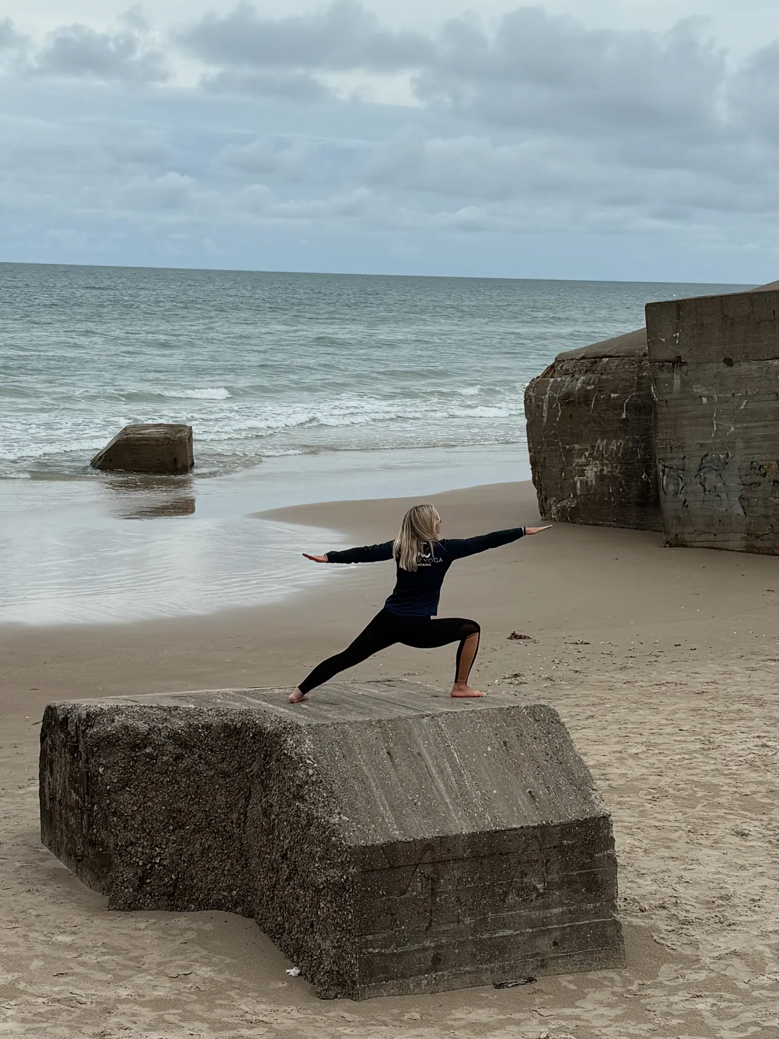 Krigeren II på en betongblokk ved sandstrand med hav i bakgrunnen