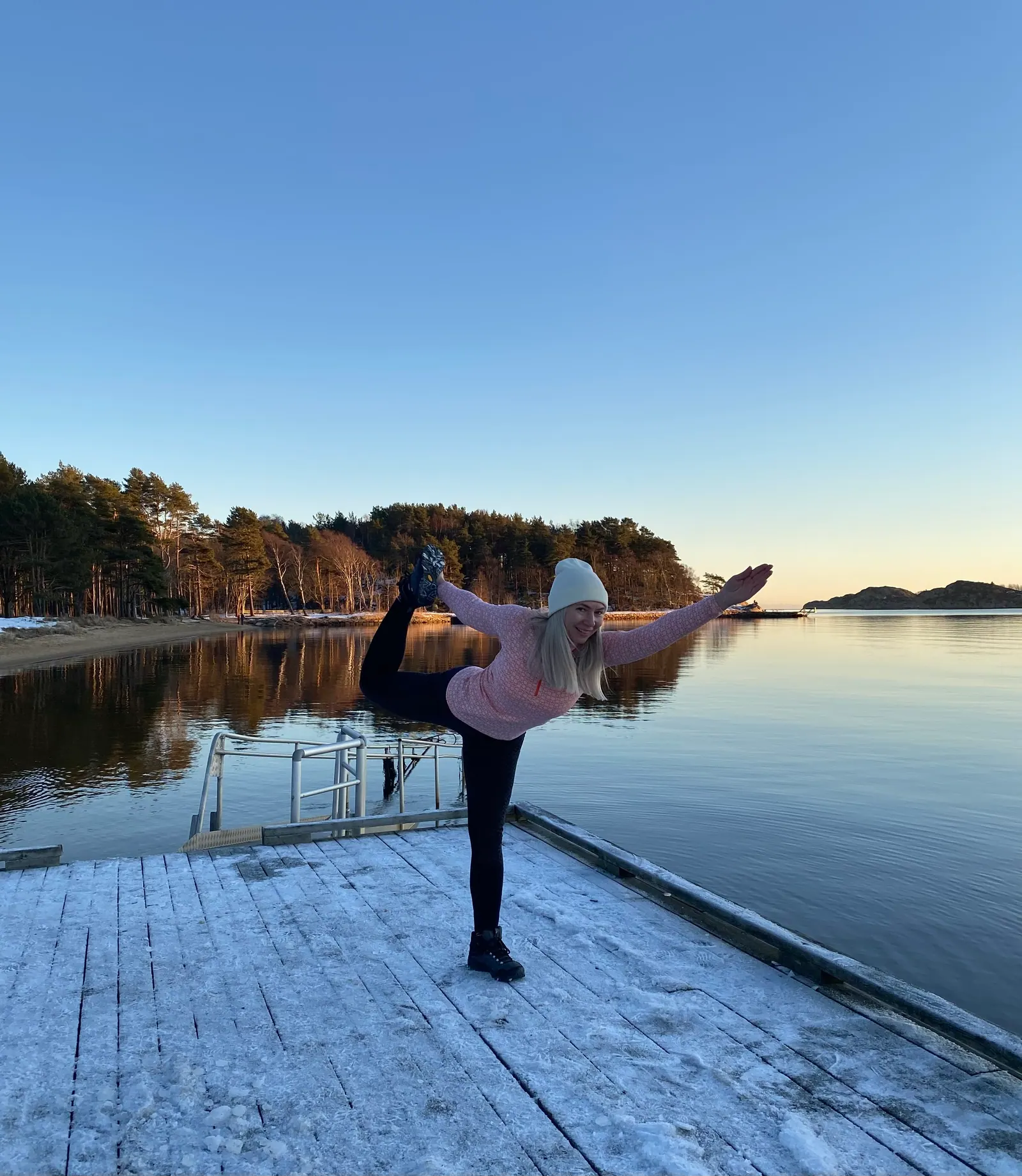 Danserpositur på snøkledd brygge ved spegelblankt vann i kveldslys