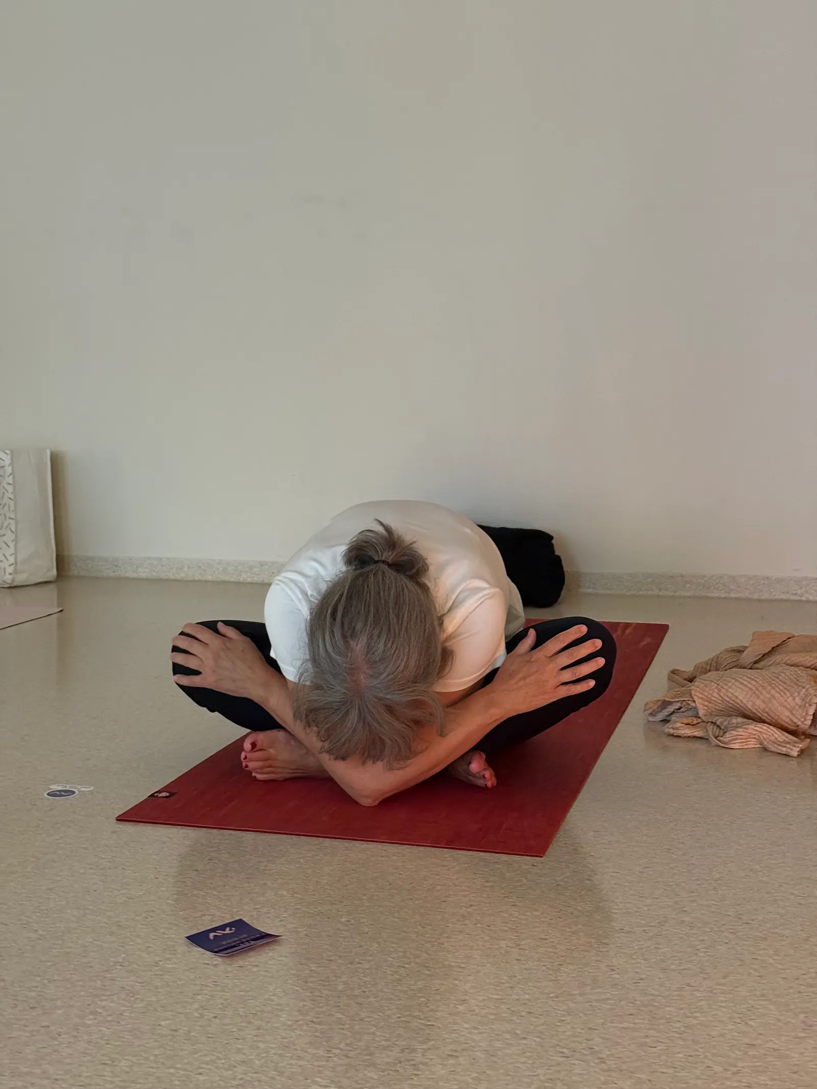 Forward fold på rød yogamatte i studioet