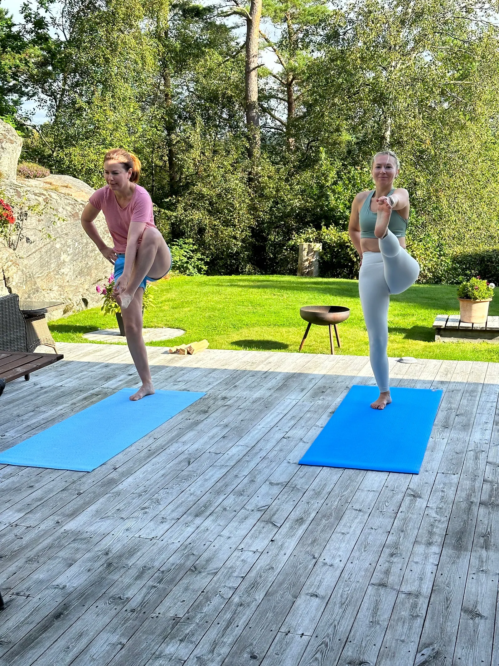 To deltakere i kriger-stilling på matter på en terrasse i sommerlys